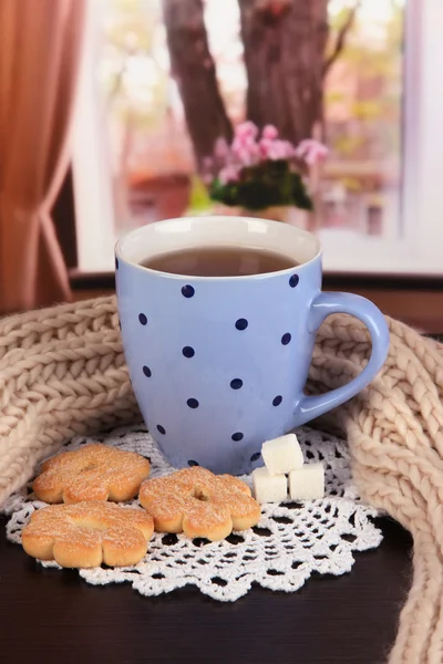 Cup of tea with scarf on table in room — Stock Photo, Image