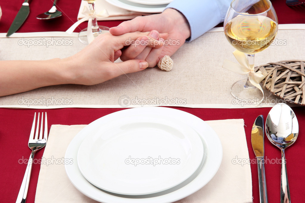 hands of romantic couple over a restaurant table