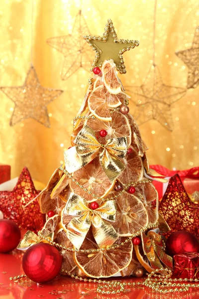 Schöner Weihnachtsbaum aus trockenen Zitronen mit Dekor, auf gelbem Hintergrund — Stockfoto