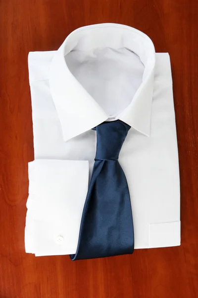 New white man 's shirt with color tie on wooden background — стоковое фото