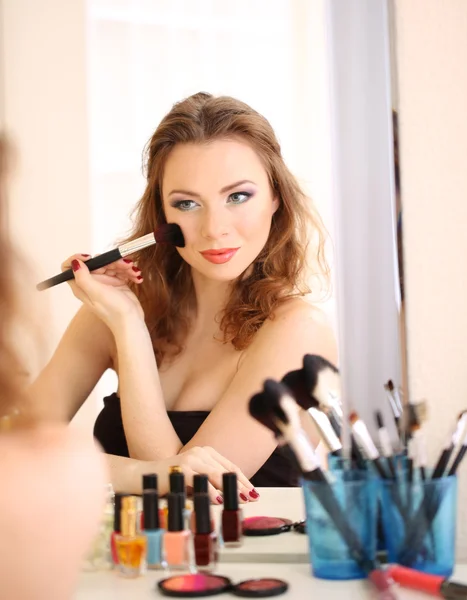 Joven hermosa mujer haciendo maquillaje cerca del espejo — Foto de Stock