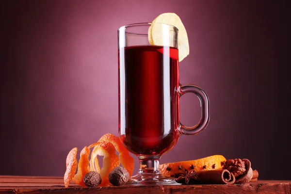 Vinho quente no copo, tempero e limão no fundo roxo — Fotografia de Stock