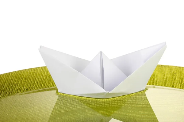 Color paper ship in water on green plate, close-up — Stock Photo, Image