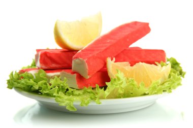 Yengeç sopalarla marul yaprakları ve plaka üzerinde beyaz izole limon