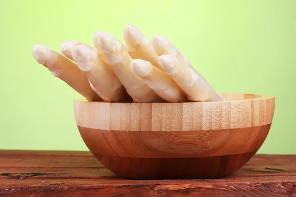 Beautiful white asparagus in bowl on wooden table on green background — Stock Photo, Image