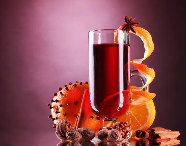 Mulled wine in the glass, spice and orange on purple background — Stock Photo, Image