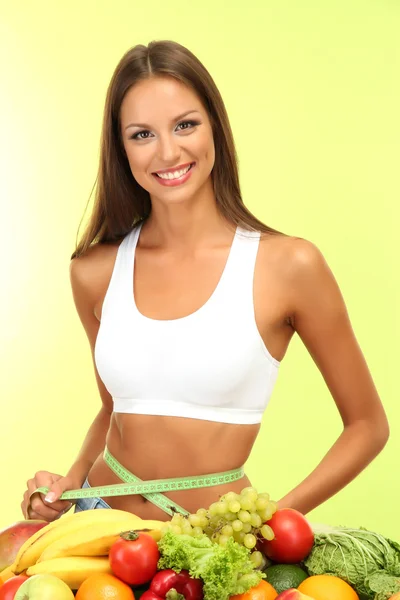 Hermosa joven con frutas y verduras, sobre fondo verde — Foto de Stock