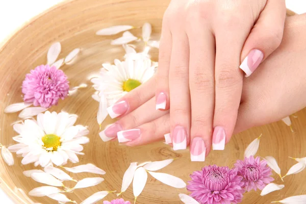 Kobieta ręce z Francuski manicure i kwiaty w bambus miska z wodą — Zdjęcie stockowe