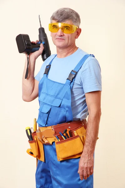 Builder with drill on wall background — Stock Photo, Image