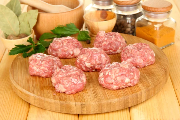 Raw meatballs with spices on wooden table — Stock Photo, Image