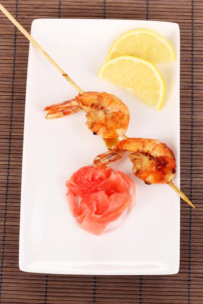 Shrimp skewers on plate with ginger and lemon — Stock Photo, Image