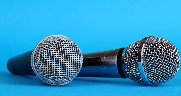 Silver and black microphones on blue background — Stock Photo, Image