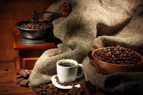 Coffee grinder and cup of coffee on brown wooden background — Stock Photo, Image