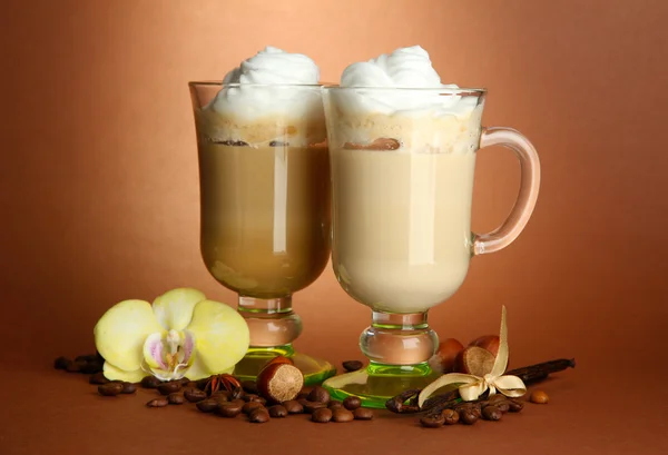 Café latte parfumé dans des tasses à verres avec des épices, sur fond brun — Photo