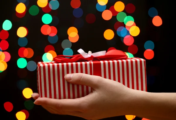 Main de femme avec boîte cadeau, sur fond de guirlande — Photo