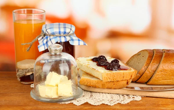 Butter on glass saucer with glass cover and fresh bread, jam on bright background — Stock Photo, Image