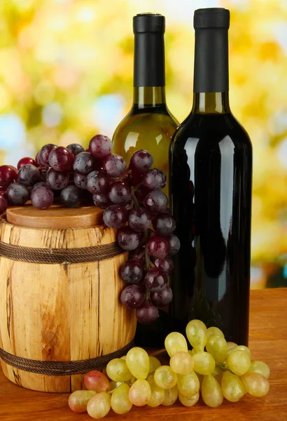 Композиция вина и винограда на деревянном бочке на ярком фоне — стоковое фото