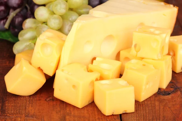 Cut cheese with grape on wooden table — Stock Photo, Image