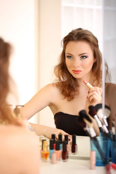 Ung vacker kvinna gör make-up nära spegeln — Stockfoto