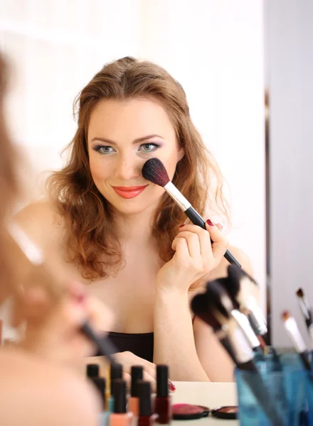 Junge schöne Frau schminkt sich in Spiegelnähe — Stockfoto