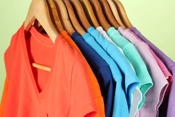 Variedad de camisas casuales en perchas de madera, sobre fondo azul — Foto de Stock