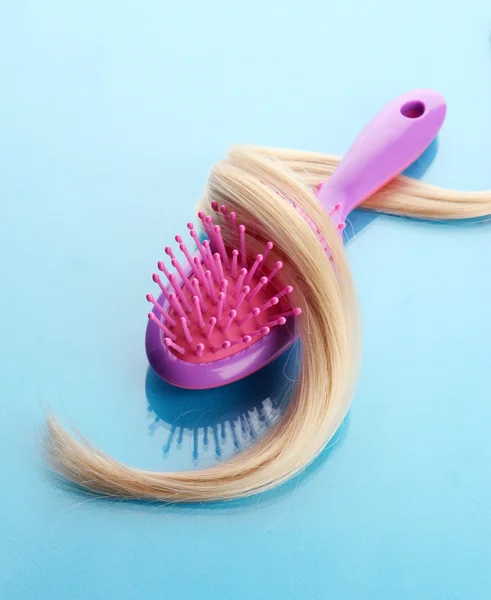 Cepillo de peine con pelo, sobre fondo azul — Foto de Stock
