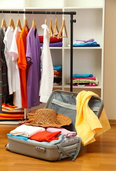 Open silver suitcase with clothing in room