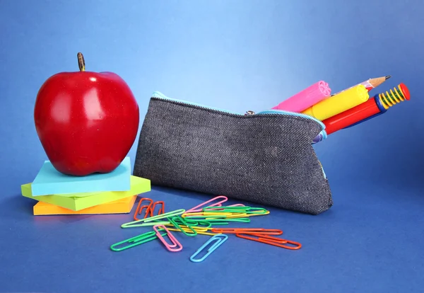 Caja de lápiz con equipo escolar sobre fondo azul — Foto de Stock