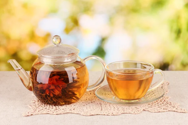 Exotische groene thee met bloemen in glas theepot op lichte achtergrond — Stockfoto