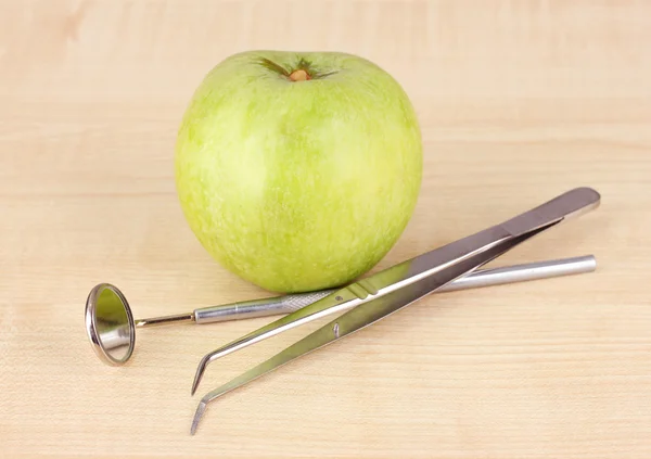 Grönt äpple och dental verktyg på trä bakgrund — Stockfoto