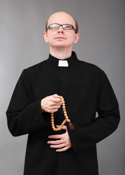 Young pastor with wooden rosary, on gray background — Stock Photo, Image