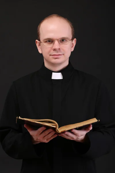 Mladý pastor s Bibli, izolované na černém pozadí — Stock fotografie