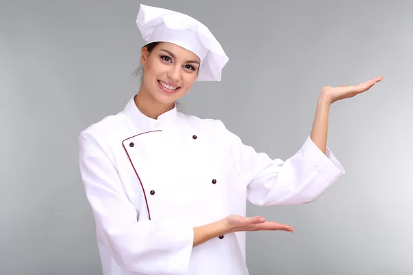 Retrato de una joven chef sobre fondo gris — Foto de Stock