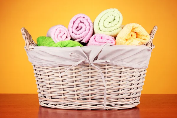 Kleurrijke handdoeken in mand op kleur achtergrond — Stockfoto