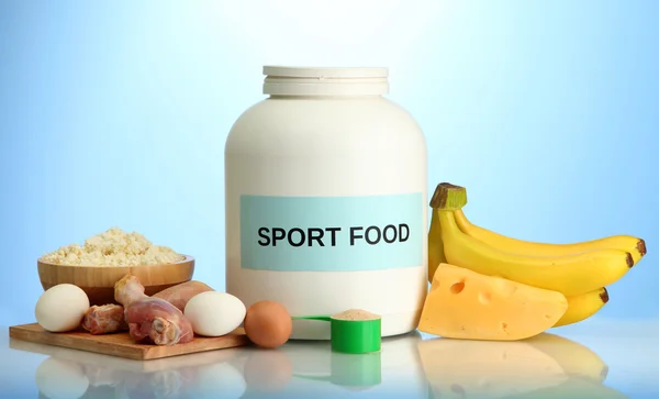 Frasco de proteína em pó e alimentos com proteína, sobre fundo azul — Fotografia de Stock