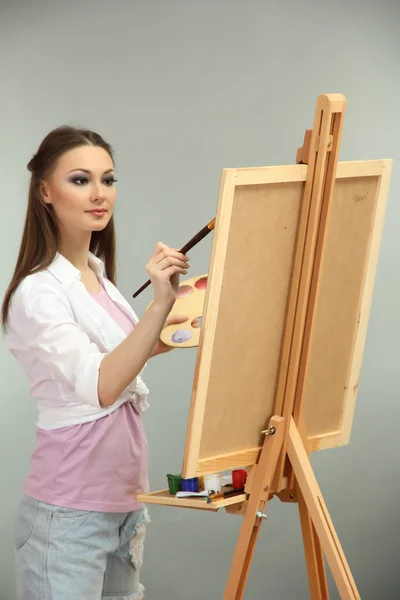 Beautiful young woman painter at work, on grey background — Stock Photo, Image