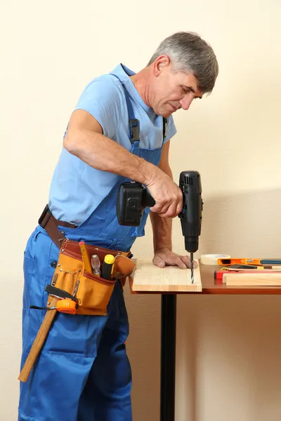 Builder drills board on table on wall background Stock Photo