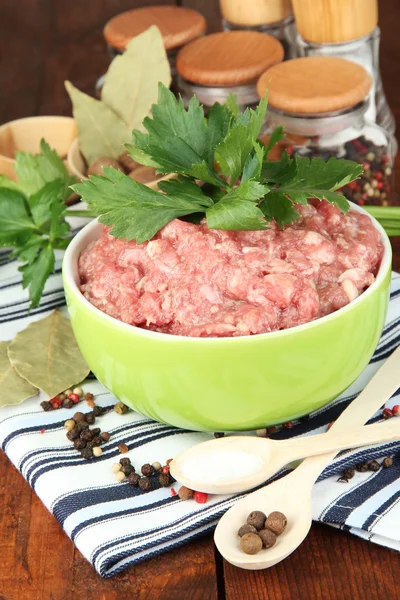 Bowl of raw ground meat with spices on wooden table Stock Image