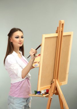 güzel bir genç kadın ressam gri arka plan üzerinde iş başında