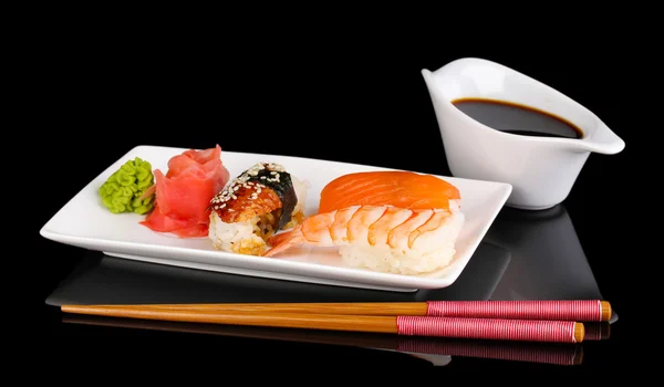 Pyszne sushi serwowane na płytkę na czarnym tle — Zdjęcie stockowe