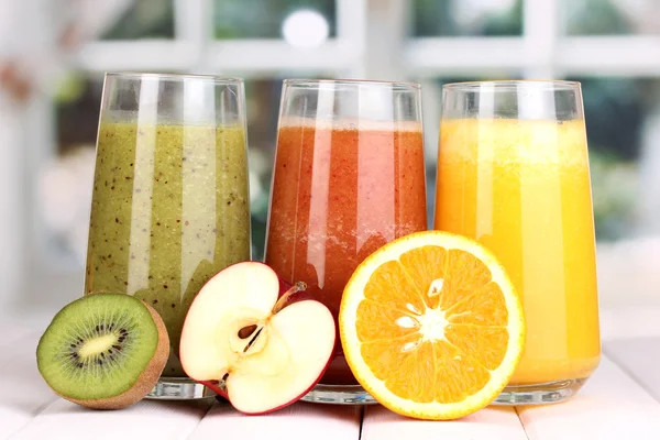 Zumos de frutas frescas sobre mesa de madera, sobre fondo de ventana —  Fotos de Stock