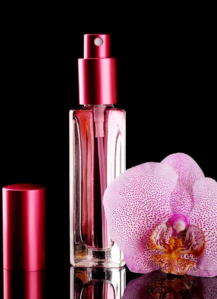 Vrouw perfume in mooie fles en orchideebloem, op zwarte achtergrond — Stockfoto