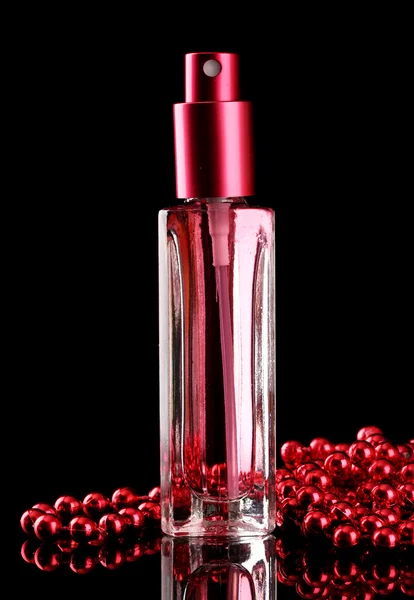 Parfum de femme en belle bouteille et perles, sur fond noir — Photo