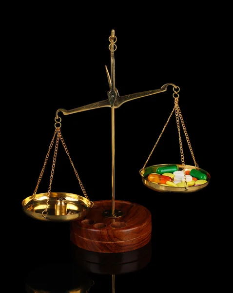 Balanças clássicas com pílulas coloridas isoladas em preto — Fotografia de Stock
