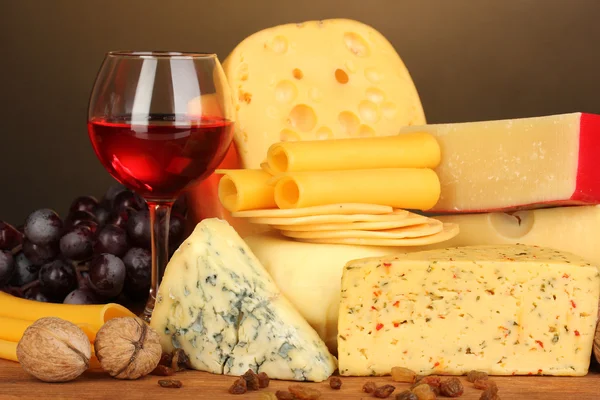 Varios tipos de queso sobre mesa de madera sobre fondo marrón — Foto de Stock