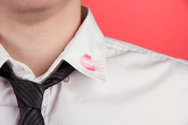 Lippenstift-Kuss auf Hemdkragen des Mannes, auf rotem Hintergrund — Stockfoto