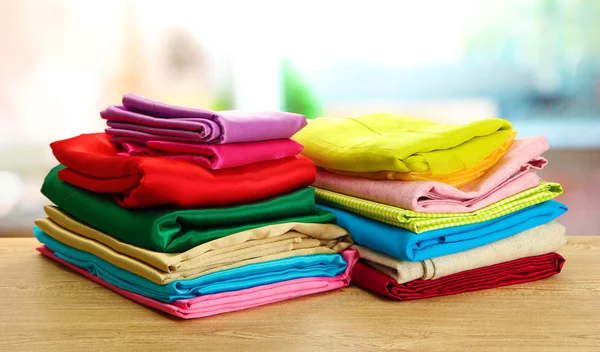 Heap of cloth fabrics on wooden table — Stock Photo, Image