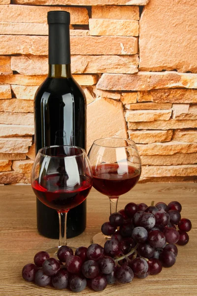 Composition of wine and grapes on table on brick wall background — Stock Photo, Image