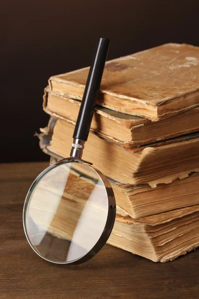 Magnifying glass and books on brown background — Stock Photo, Image