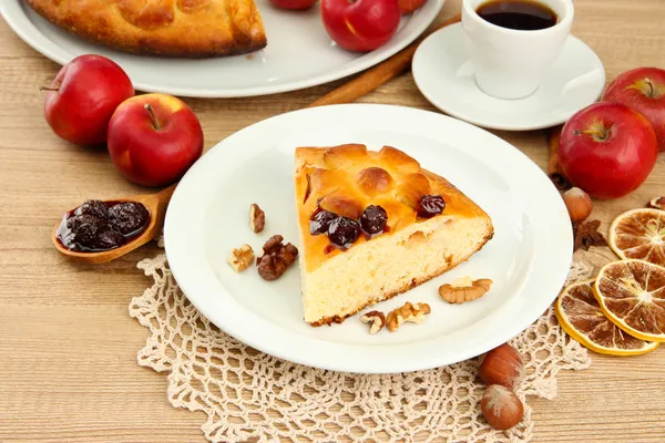 Tranche de tarte maison savoureuse avec confiture et pommes et tasse de café, sur une table en bois — Photo